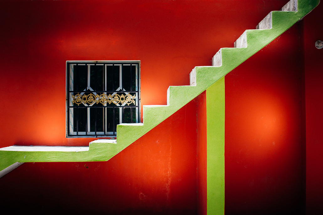 ﻿Green staircase against red wall a with blue and gold barred window